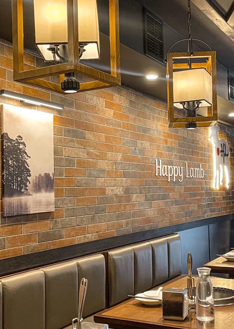 Booth seating along a brick wall with the Happy Lamb sign and lit lamb logo